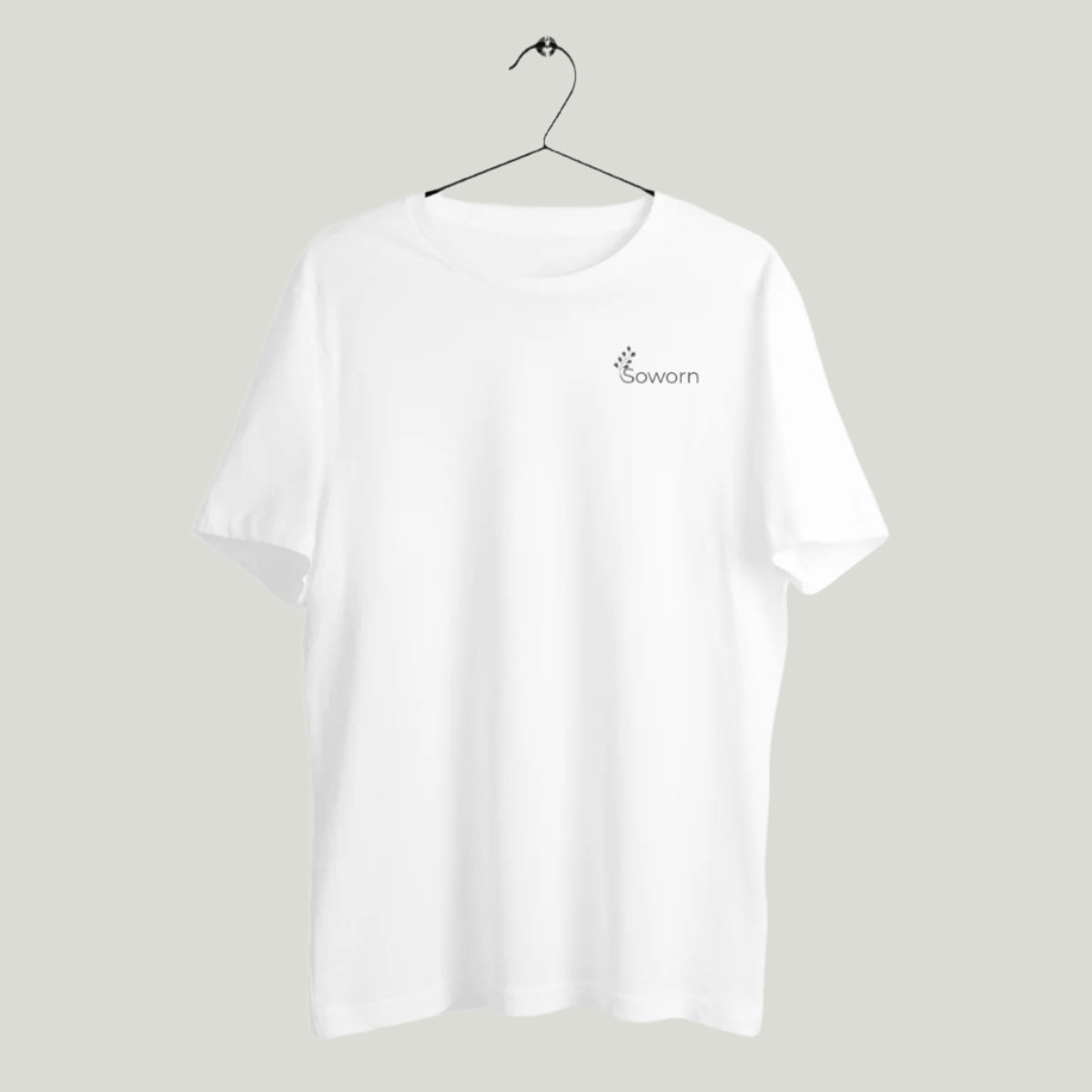 White unisex t-shirt hanging on a minimalist hanger, with the Soworn logo printed on the left chest, against a light gray background.